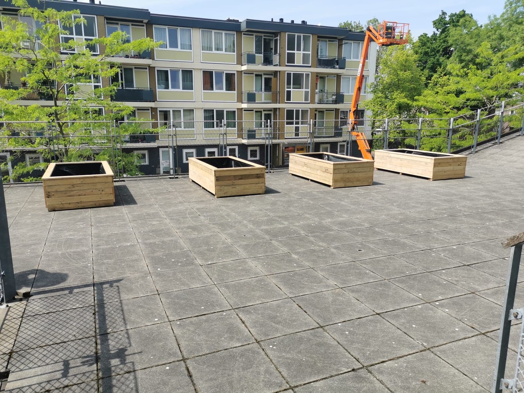 Vier houten plantenbakken op maat op een dakterras bij een appartementencomplex