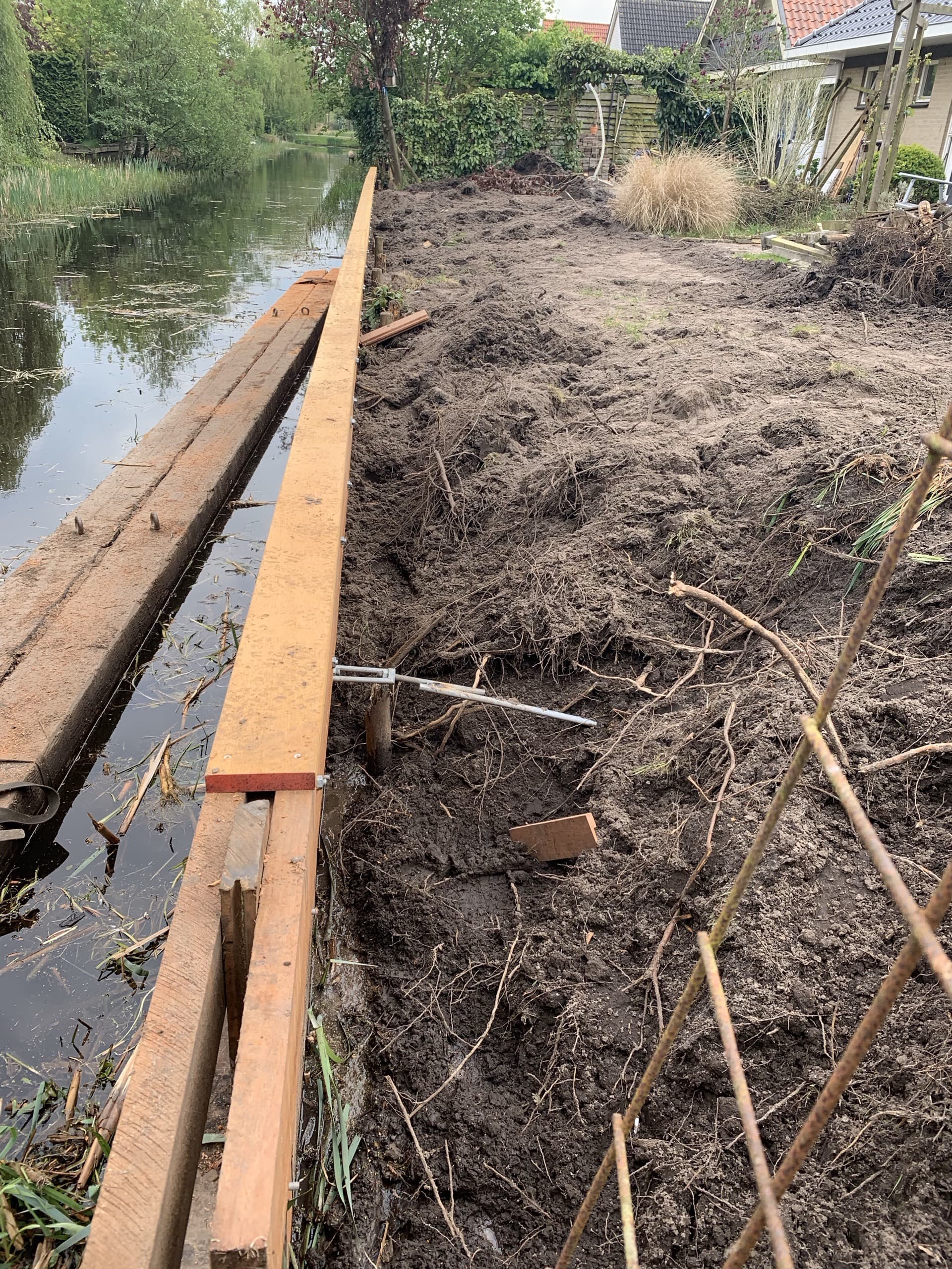 De grond direct achter de nieuwe beschoeiing, met een leidingdoorvoer die tijdens het werk is vrijgegraven
