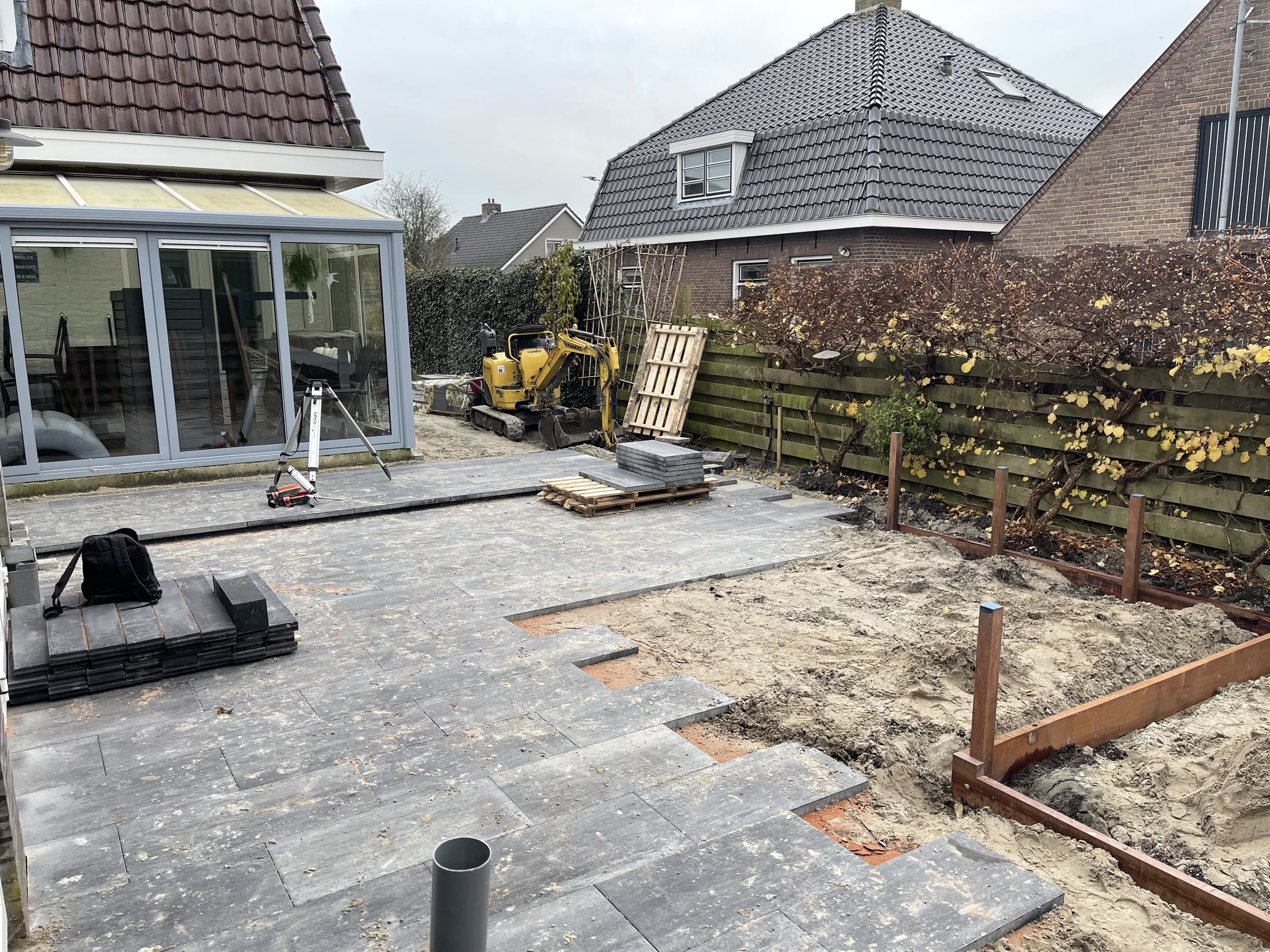 De achtertuin in Warten tijdens de aanleg: een minigraver naast het net gelegde terras