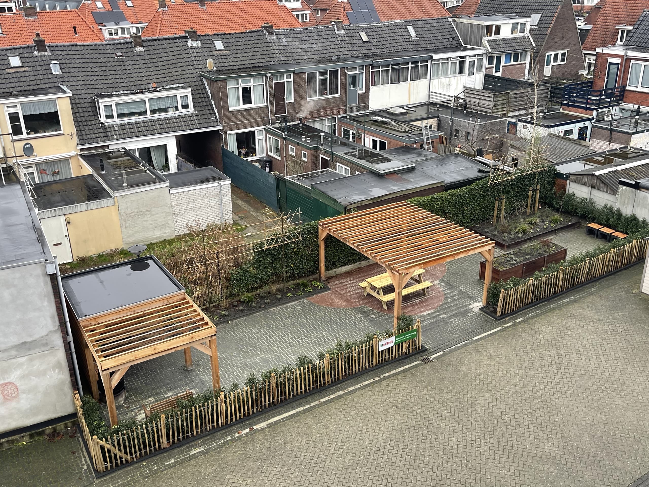 Luchtfoto van de twee overkappingen met de moestuinbakken en de haag langs de erfafscheiding aan de andere kant van de tuin