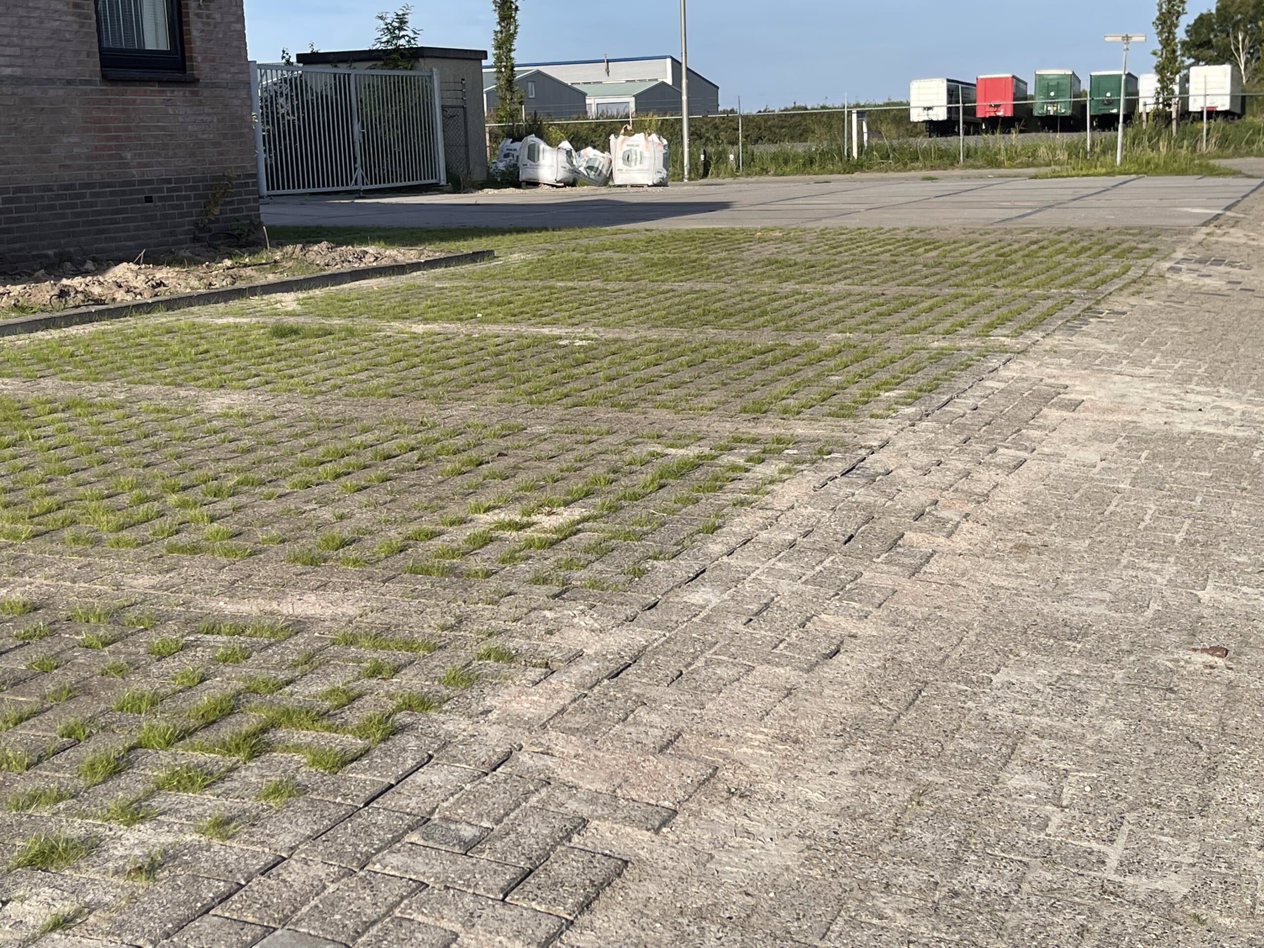 Grasbetontegels op de parkeerplaats laten regenwater door en lopen over in de klinkerverharding