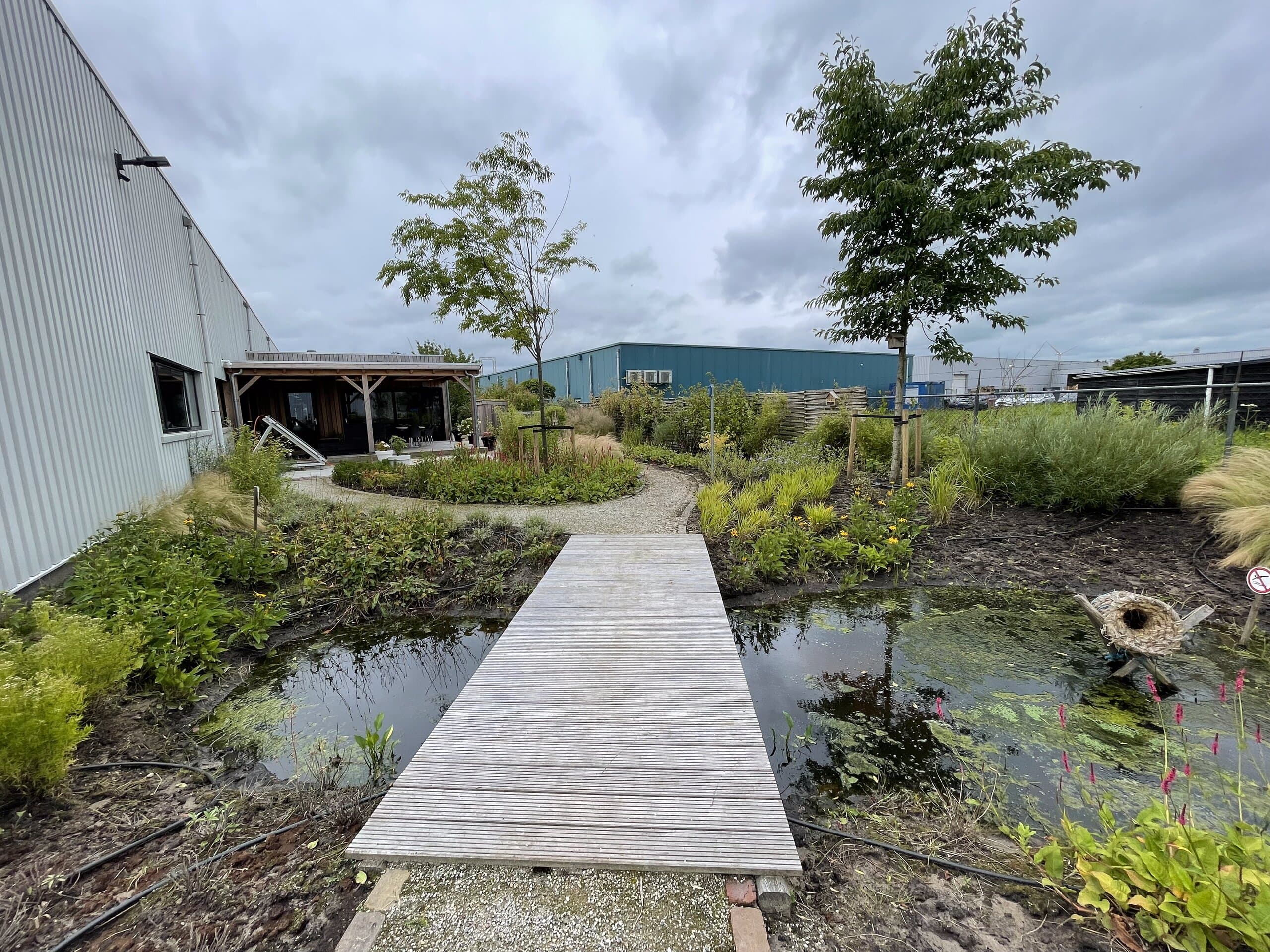 De houten brug over het water, met de overkapping van het bedrijfspand op de achtergrond
