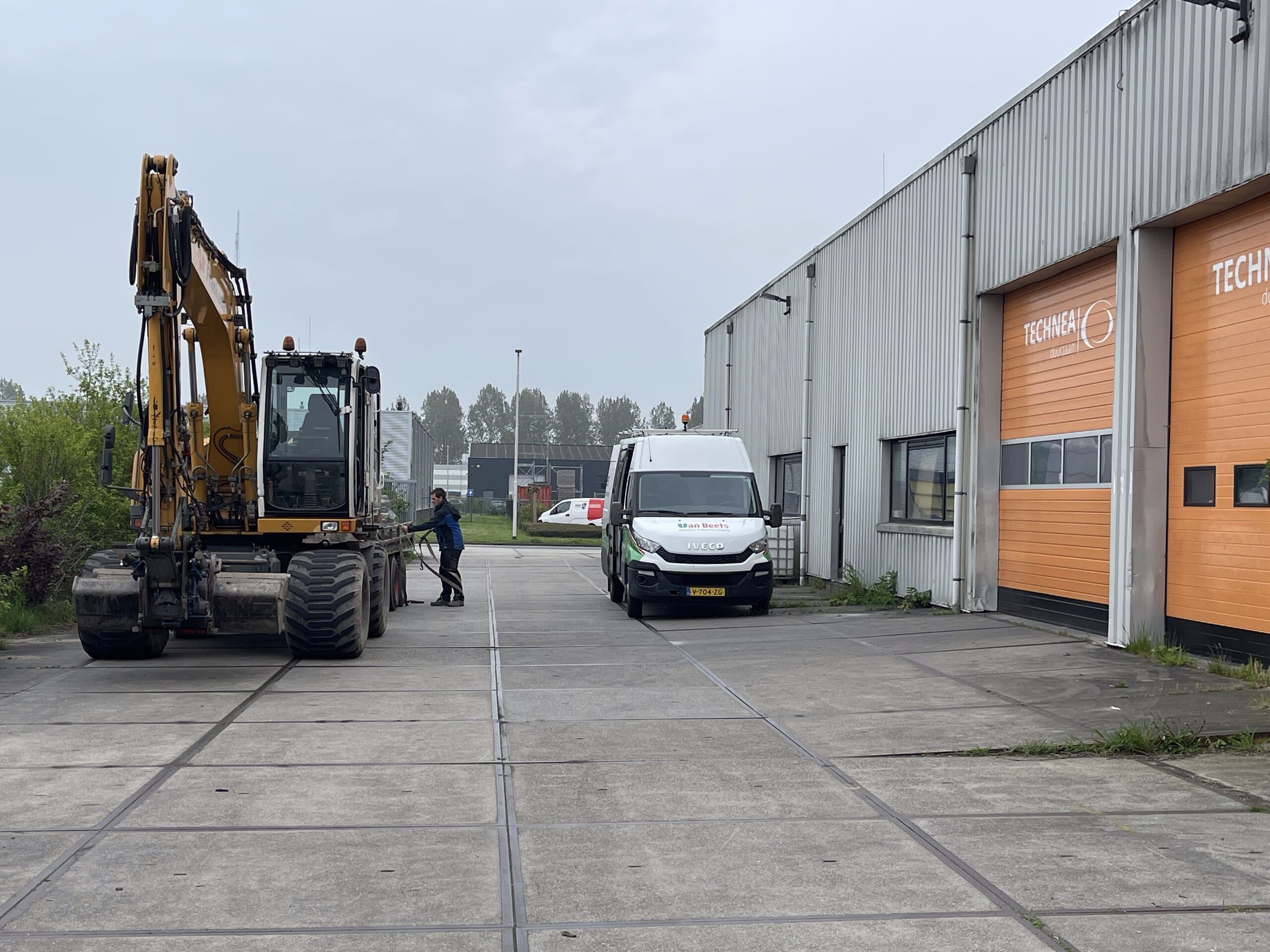 De graafmachine wordt van de dieplader gereden bij de start van het werk