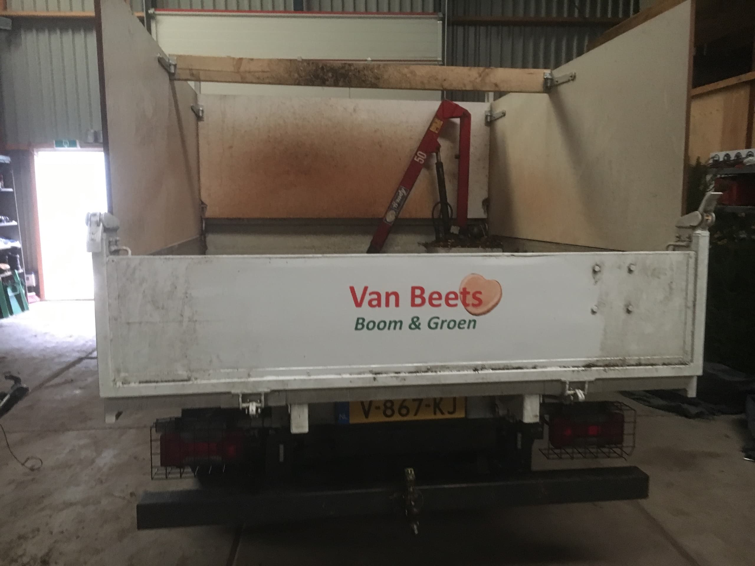 Bedrijfsbus met de belettering Van Beets Boom & Groen, geparkeerd naast een aanhanger met gereedschap