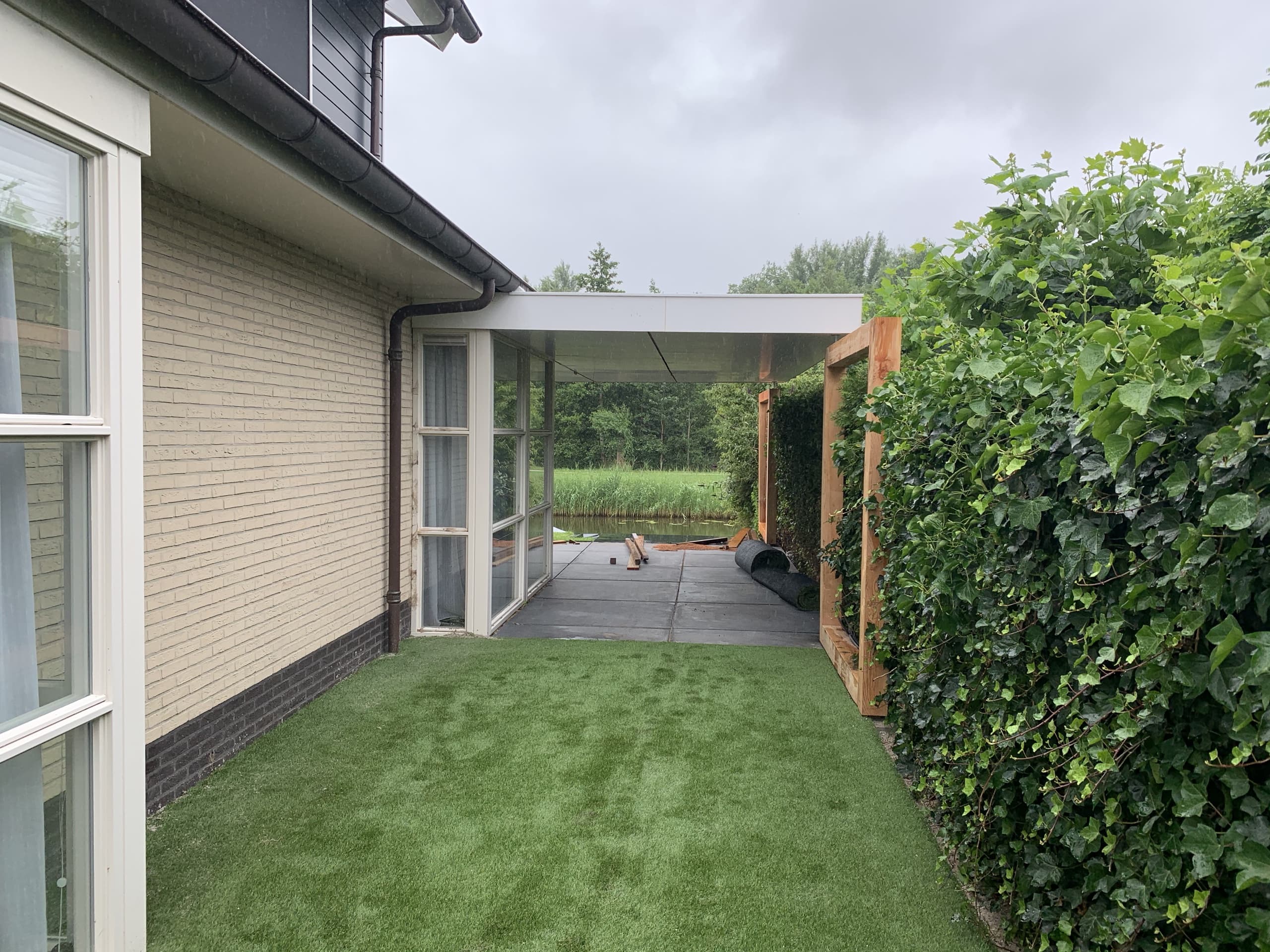 Kunstgras langs de zijgevel van een woning in Drachten, met zicht op het water achter de tuin