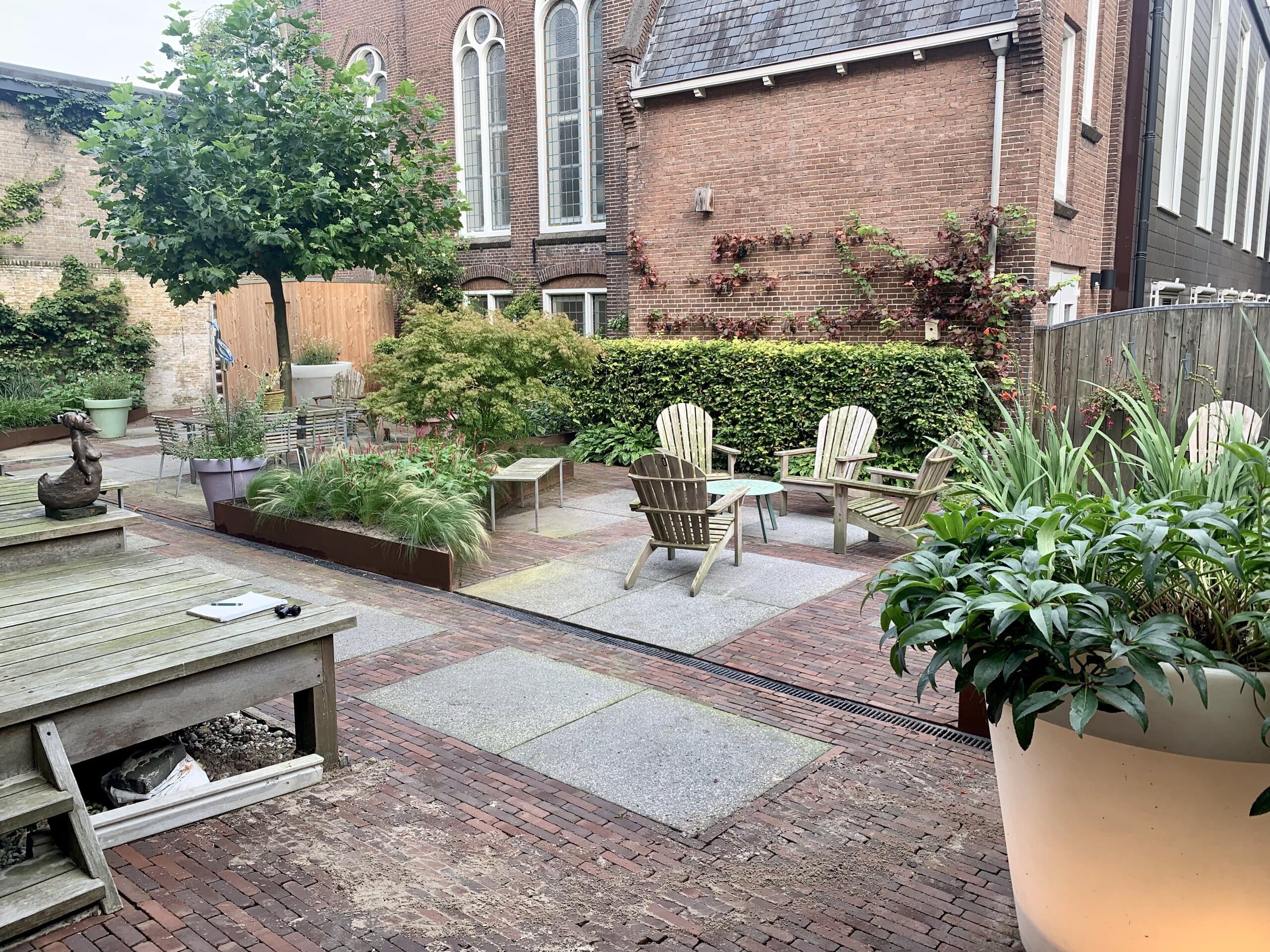 De zitplek achterin de tuin, met Japanse esdoorns en een haag langs de schutting